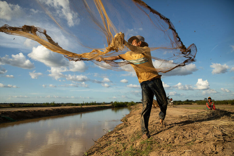 Farmer Deur Sok casts a fishing net across a canal the building of which was facilitated by WFP